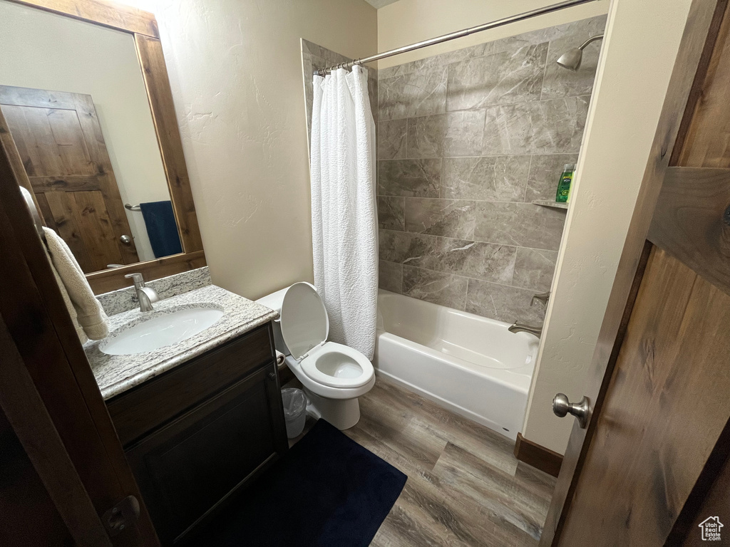 Bathroom featuring wood finished floors, vanity, toilet, and shower / bath combo with shower curtain