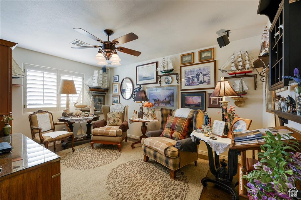 Living area with a ceiling fan and baseboards