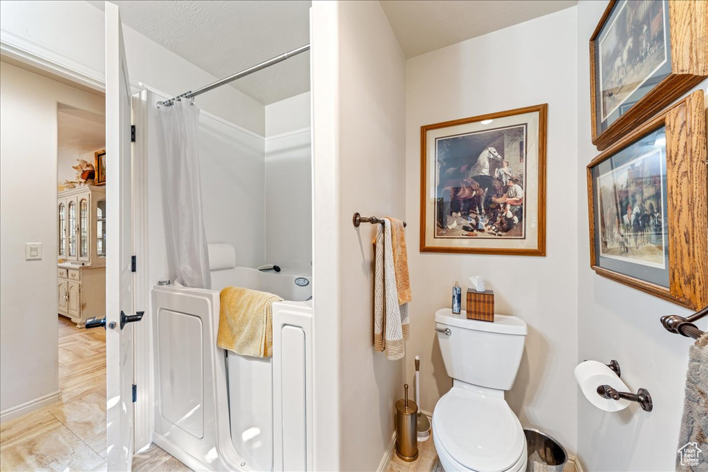 Bathroom with toilet and shower / tub combo with curtain