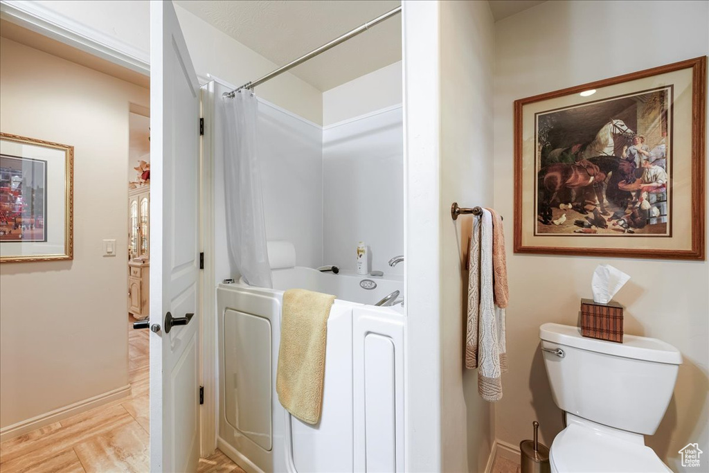 Bathroom with shower / bath combo, toilet, and baseboards