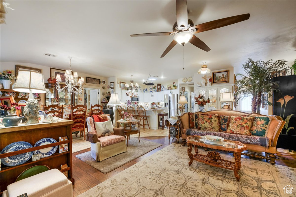 Living room with a chandelier, wood finished floors, and ceiling fan