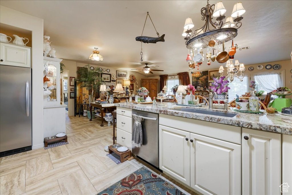 Kitchen featuring stainless steel appliances, a sink, a chandelier, ceiling fan, and white cabinets