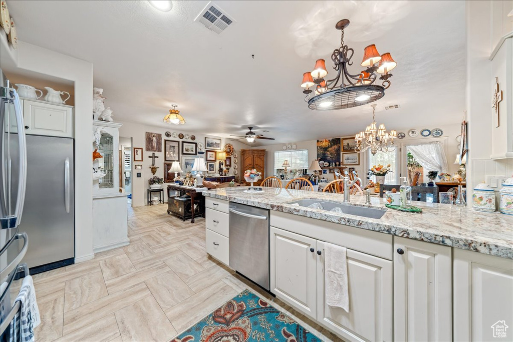 Kitchen featuring appliances with stainless steel finishes, a chandelier, a ceiling fan, and white cabinetry
