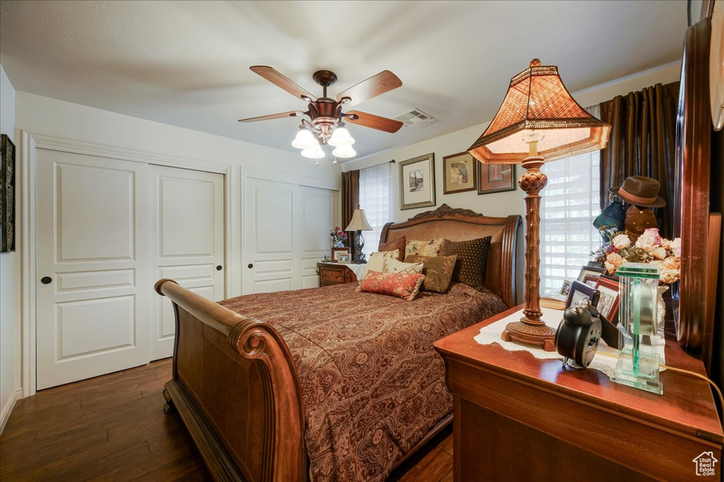 Bedroom featuring multiple closets, dark wood-type flooring, and ceiling fan