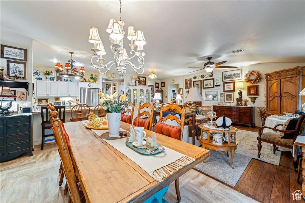 Dining room with a ceiling fan, a chandelier, and light wood finished floors