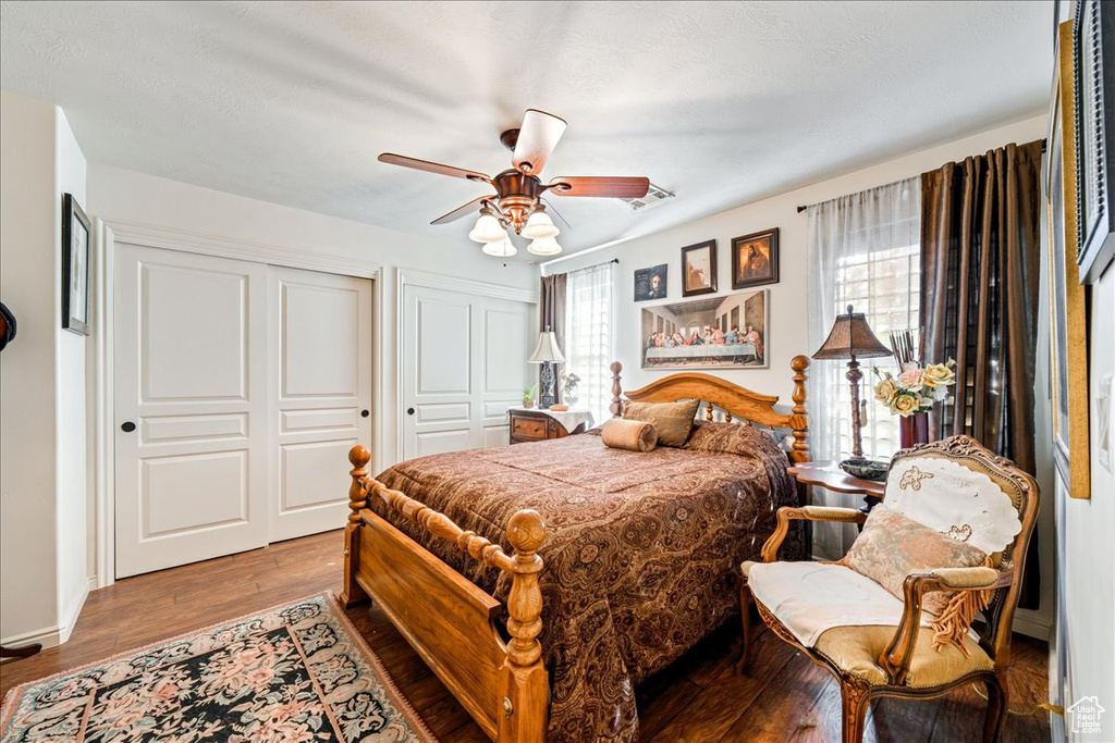 Bedroom with two closets, wood finished floors, and a ceiling fan