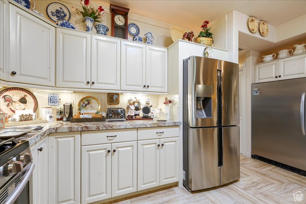 Kitchen featuring appliances with stainless steel finishes, white cabinets, and light countertops