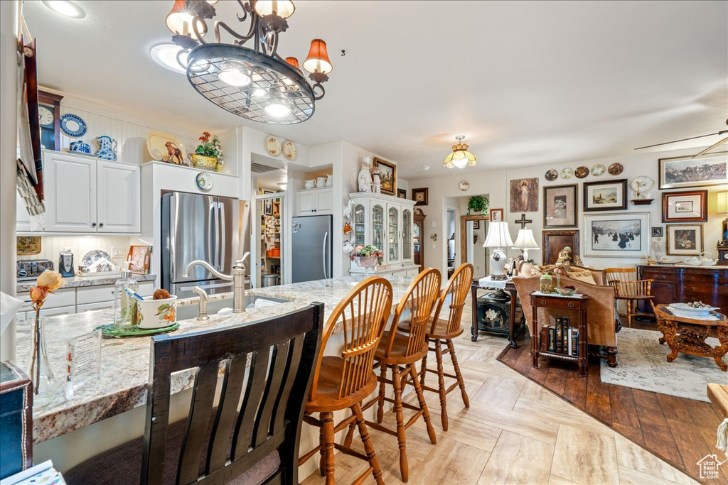 Kitchen with freestanding refrigerator, white cabinets, a chandelier, and light stone countertops