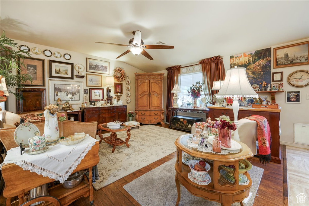 Living room with ceiling fan, wood finished floors, and lofted ceiling