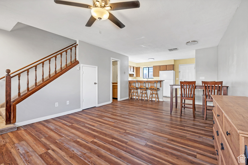 Living room with dark wood-style floors, ceiling fan, stairs, and baseboards