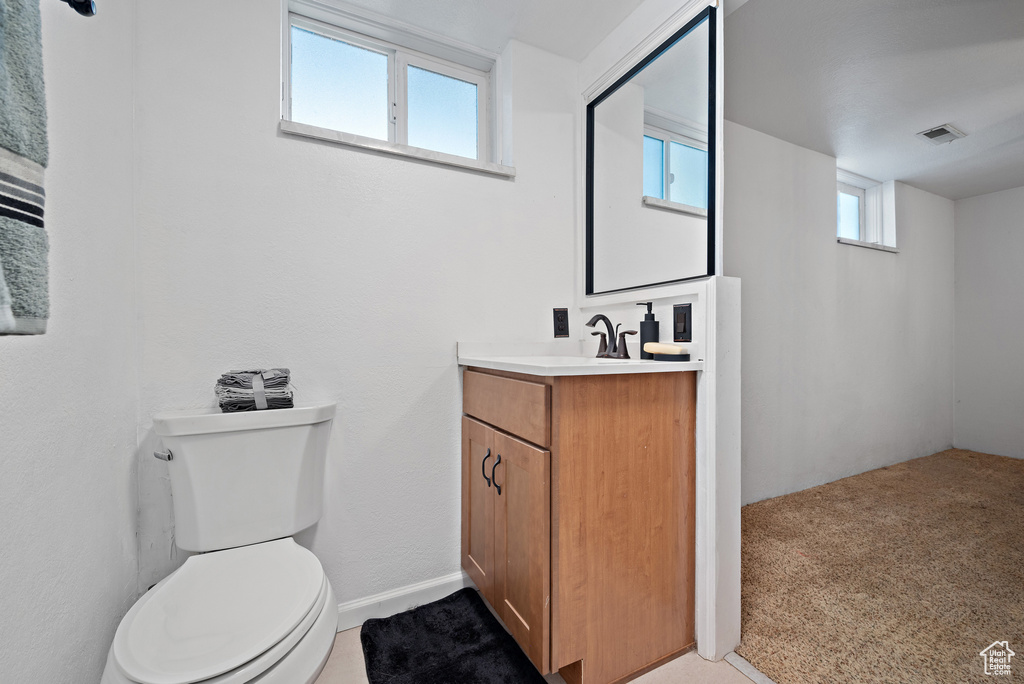 Bathroom featuring vanity, toilet, and baseboards