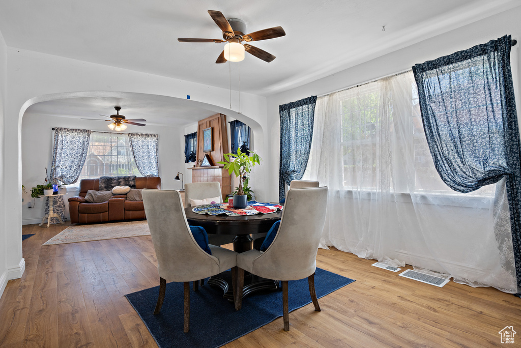 Dining area with arched walkways, a ceiling fan, and wood finished floors