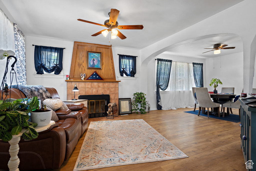 Living room with ceiling fan, plenty of natural light, arched walkways, and a tile fireplace