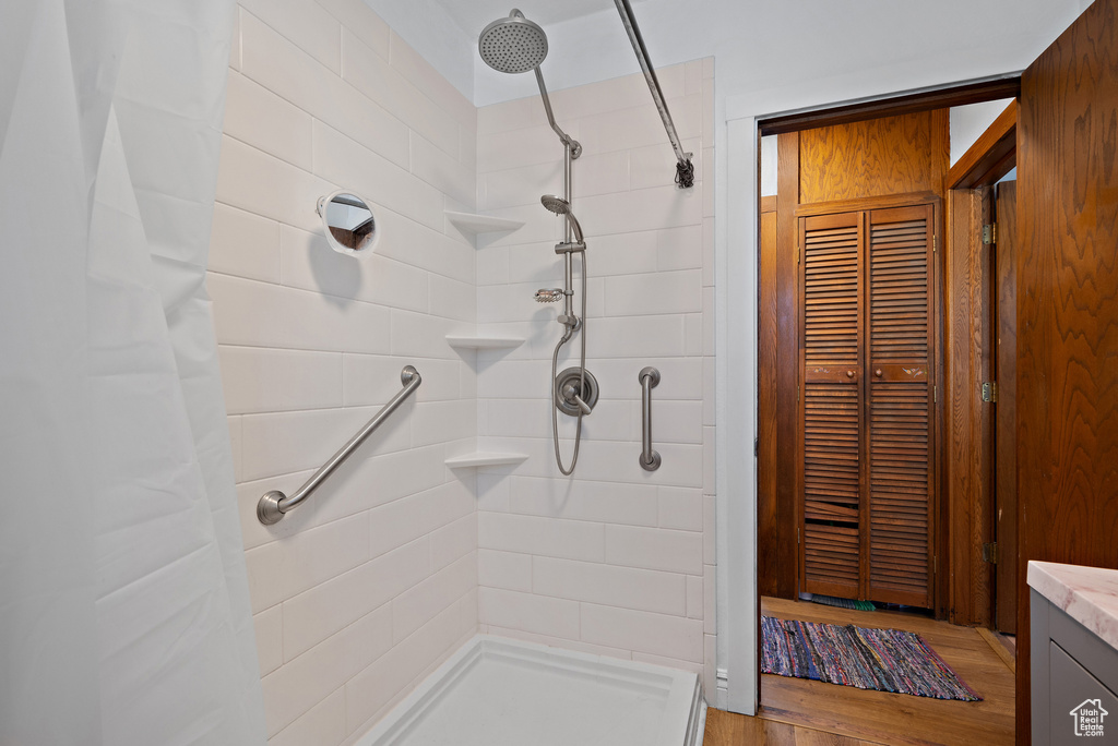 Bathroom featuring a tile shower, a closet, wood finished floors, and vanity