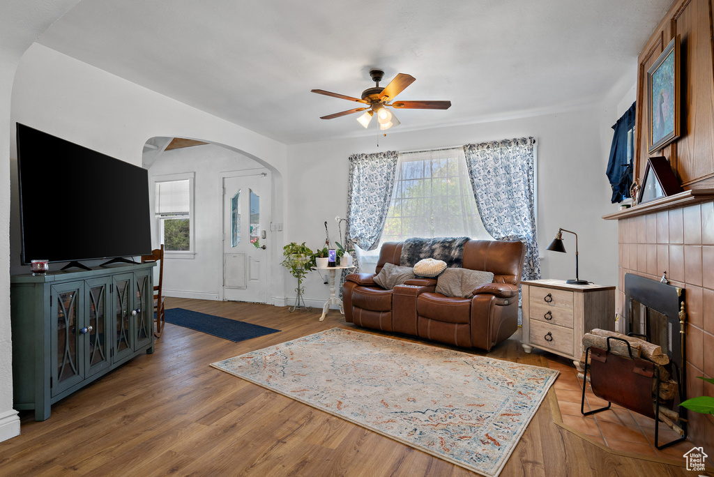 Living room with arched walkways, a ceiling fan, healthy amount of natural light, and light wood-style flooring