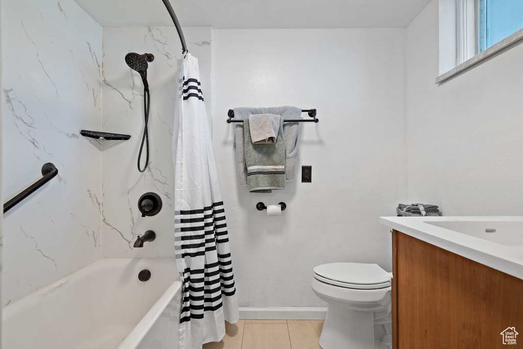 Bathroom featuring vanity, toilet, shower / tub combo with curtain, and baseboards