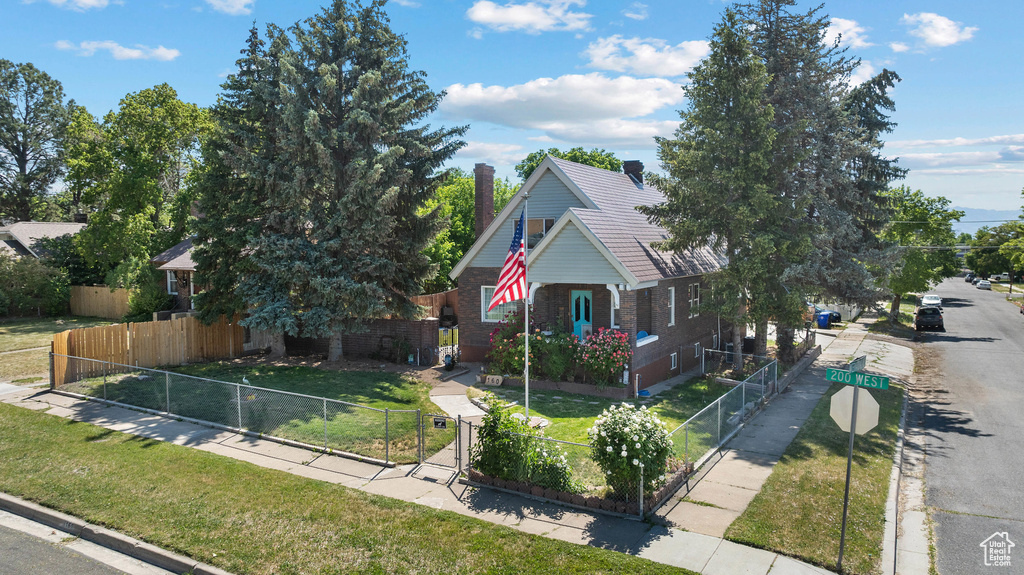View of property hidden behind natural elements featuring brick siding and a chimney