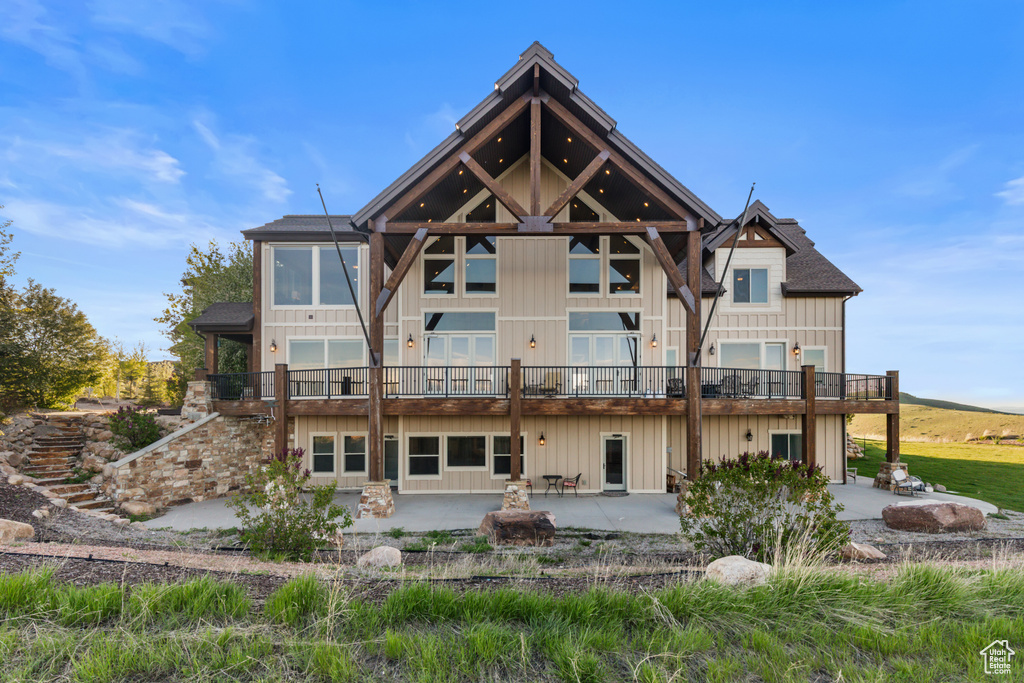 Rear view of house featuring a patio, board and batten siding, and a balcony