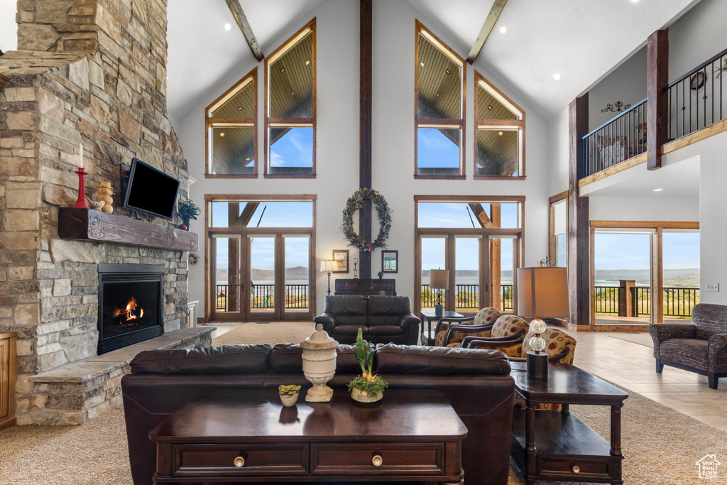 Living area with high vaulted ceiling, a stone fireplace, and beamed ceiling