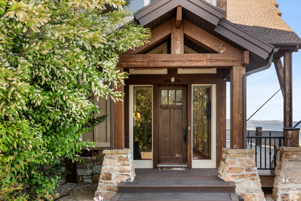 View of exterior entry with a shingled roof