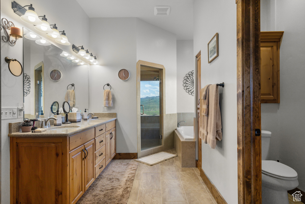 Full bathroom with double vanity, toilet, a garden tub, and baseboards