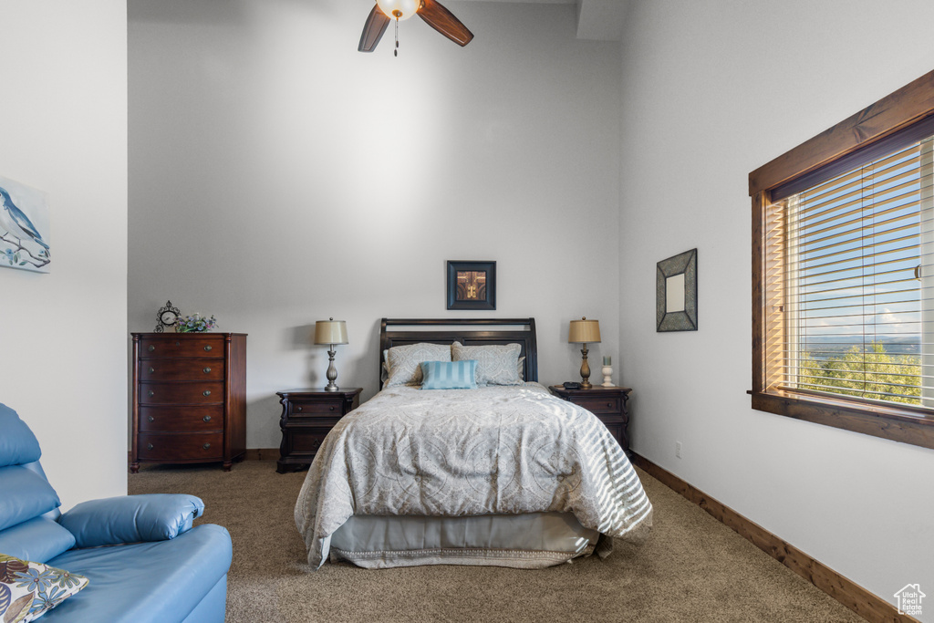 Bedroom with carpet floors, a towering ceiling, a ceiling fan, and baseboards