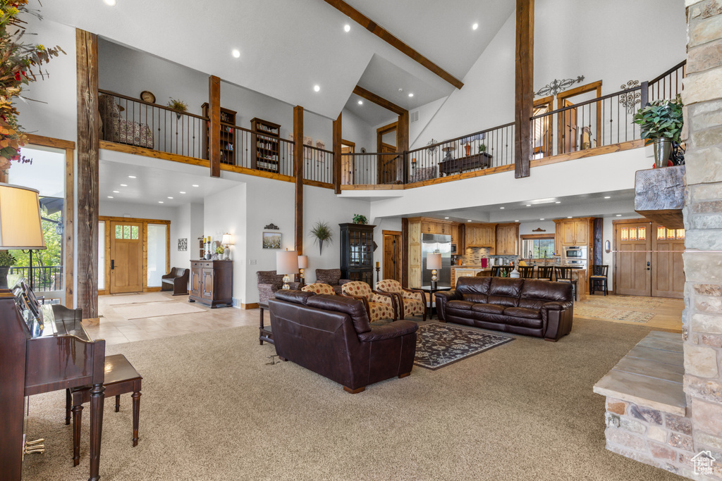 Living room with high vaulted ceiling, light carpet, recessed lighting, beamed ceiling, and baseboards