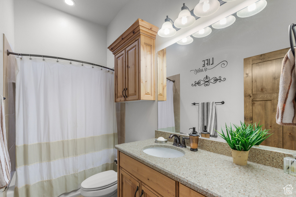 Bathroom featuring toilet, vanity, and shower / tub combo with curtain