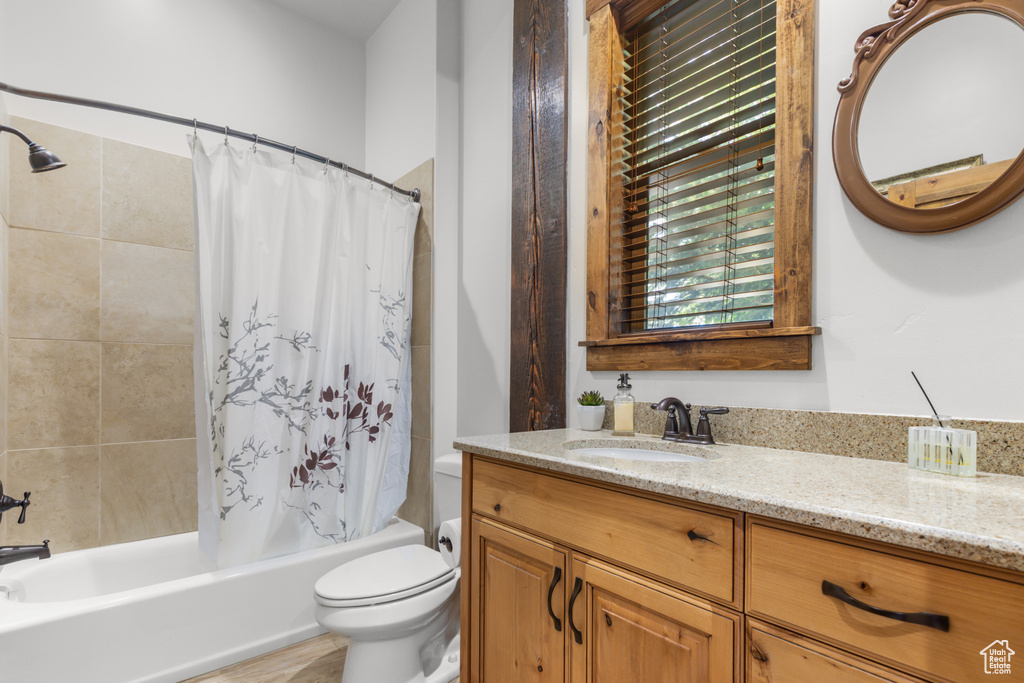 Bathroom with vanity, toilet, and shower / bathtub combination with curtain
