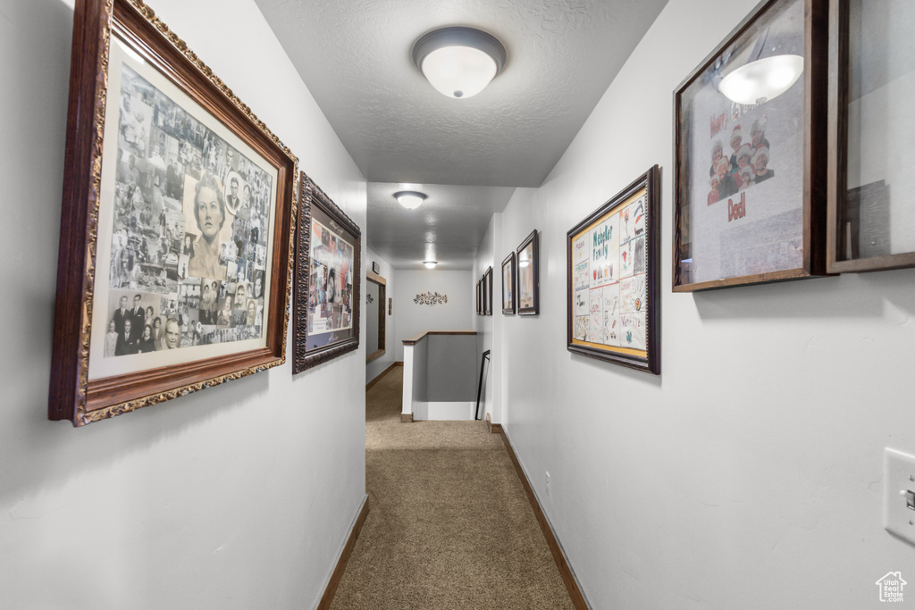 Corridor featuring carpet floors, a textured ceiling, baseboards, and an upstairs landing