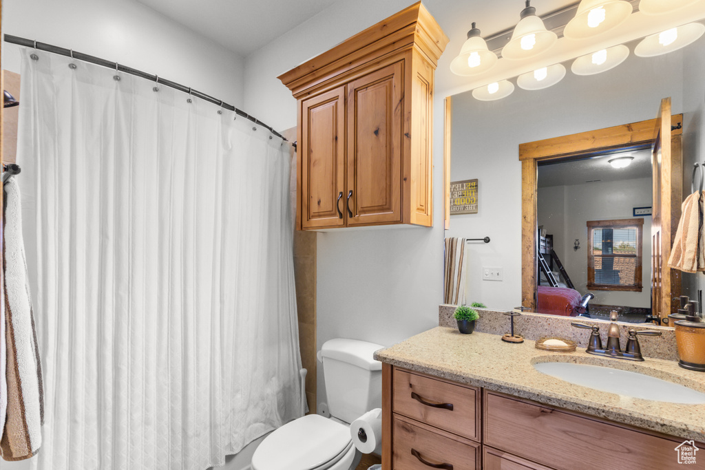 Bathroom with vanity, toilet, and curtained shower