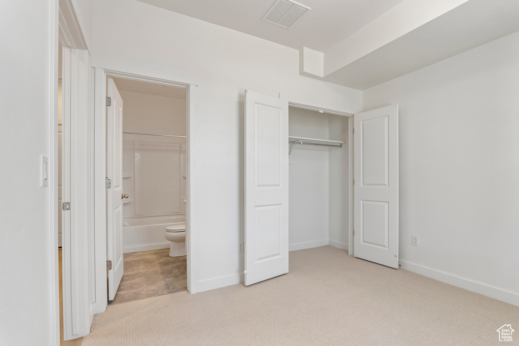 Unfurnished bedroom with carpet flooring, a closet, baseboards, and ensuite bathroom