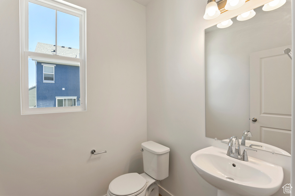 Half bath featuring a sink, toilet, and baseboards