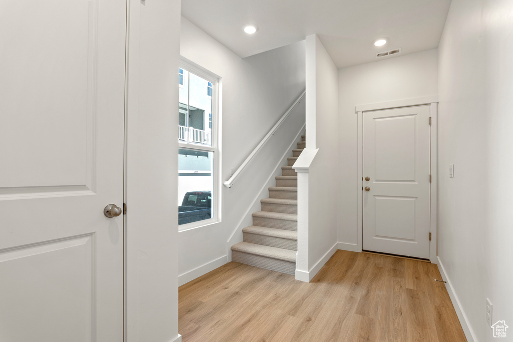 Foyer entrance with baseboards, light wood finished floors, stairway, and recessed lighting