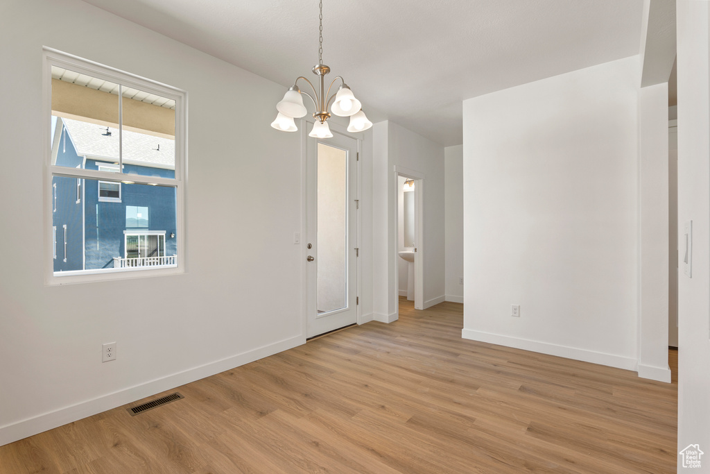Unfurnished room featuring a chandelier, wood finished floors, and baseboards