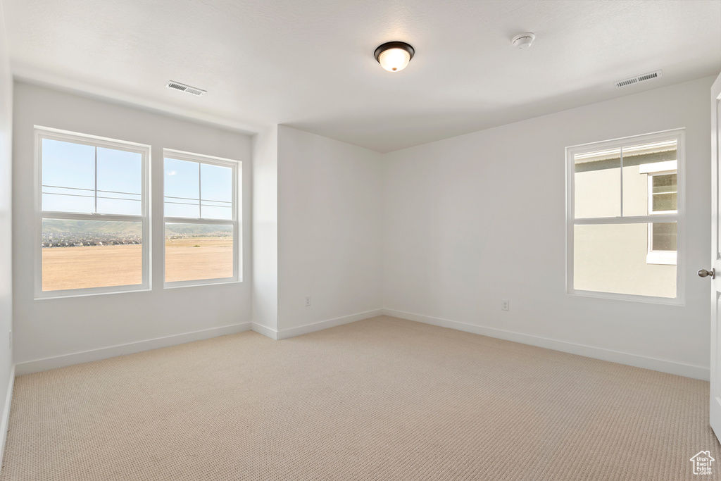 Unfurnished room with baseboards, light carpet, and a smoke detector
