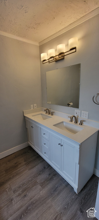 Bathroom featuring wood finished floors, double vanity, and baseboards