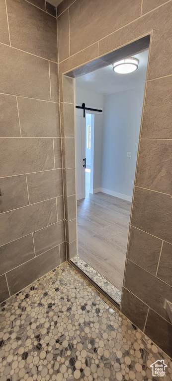 Corridor with a barn door, baseboards, and tile walls