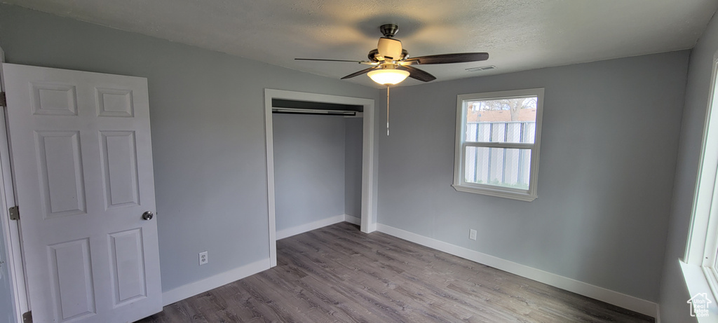 Unfurnished bedroom with baseboards, a closet, wood finished floors, and a textured ceiling