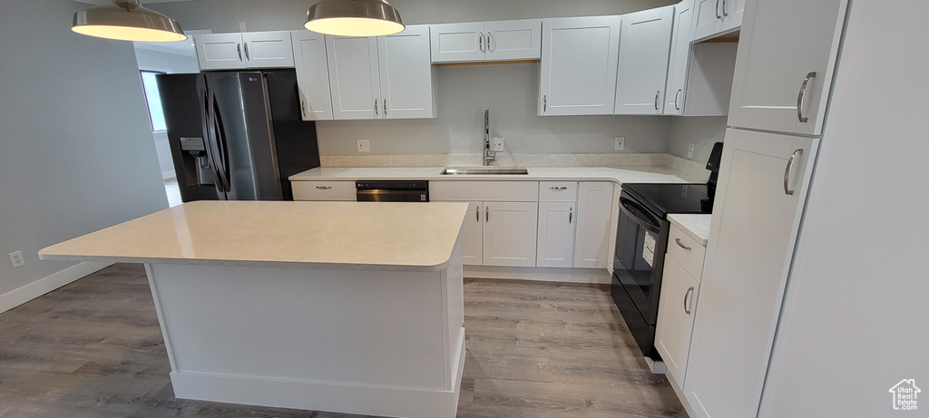 Kitchen with black electric range, fridge with ice dispenser, a sink, and light wood finished floors