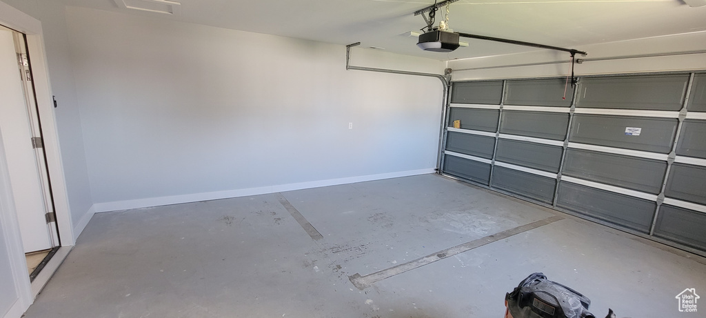 Garage featuring a garage door opener and baseboards