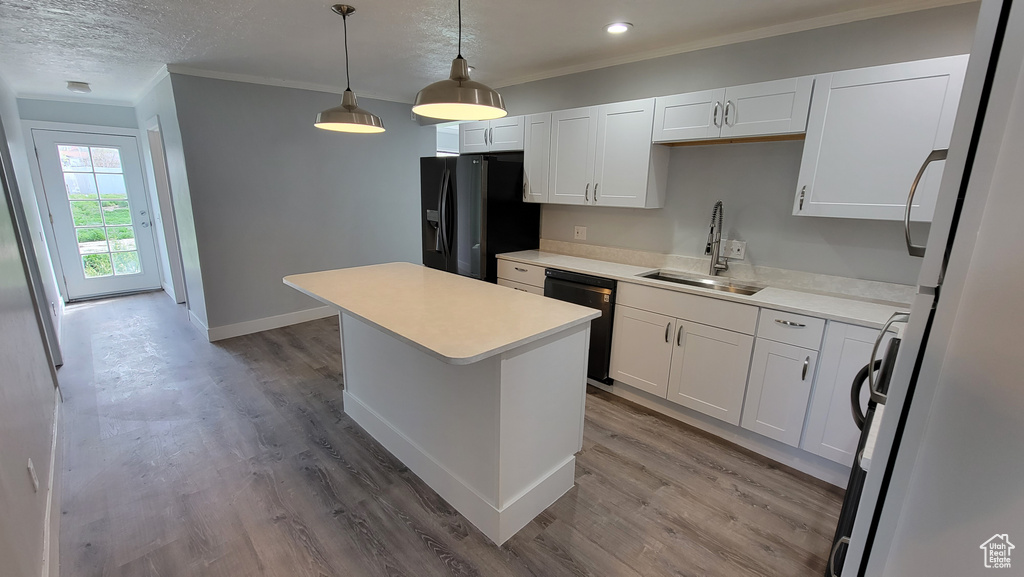 Kitchen with black appliances, a sink, ornamental molding, a kitchen island, and white cabinetry
