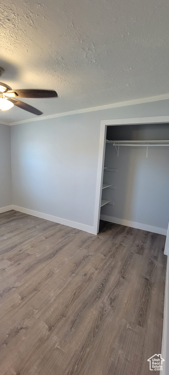 Unfurnished bedroom with a textured ceiling, wood finished floors, a closet, and baseboards
