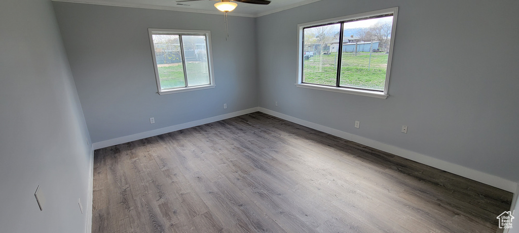 Spare room with plenty of natural light, a ceiling fan, ornamental molding, wood finished floors, and baseboards