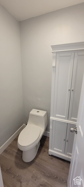 Bathroom with wood finished floors, toilet, and baseboards