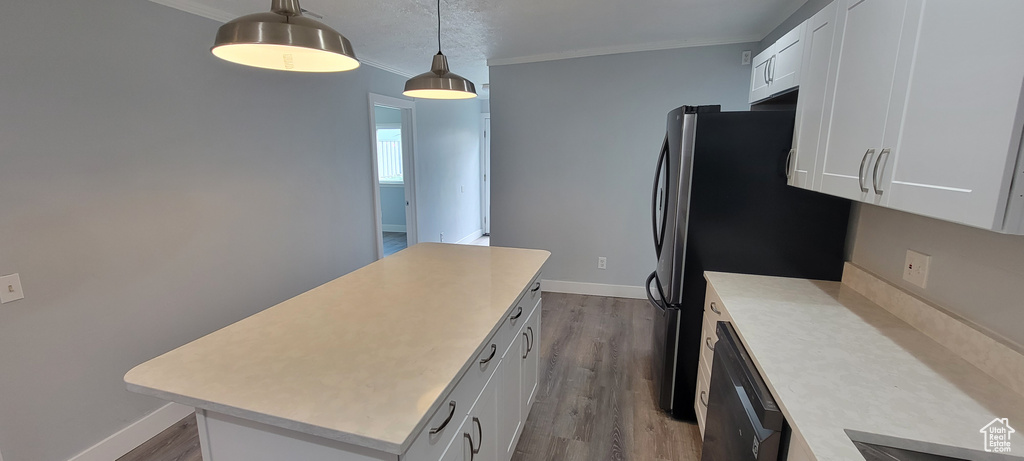 Kitchen with light countertops, a kitchen island, crown molding, white cabinets, and wood finished floors