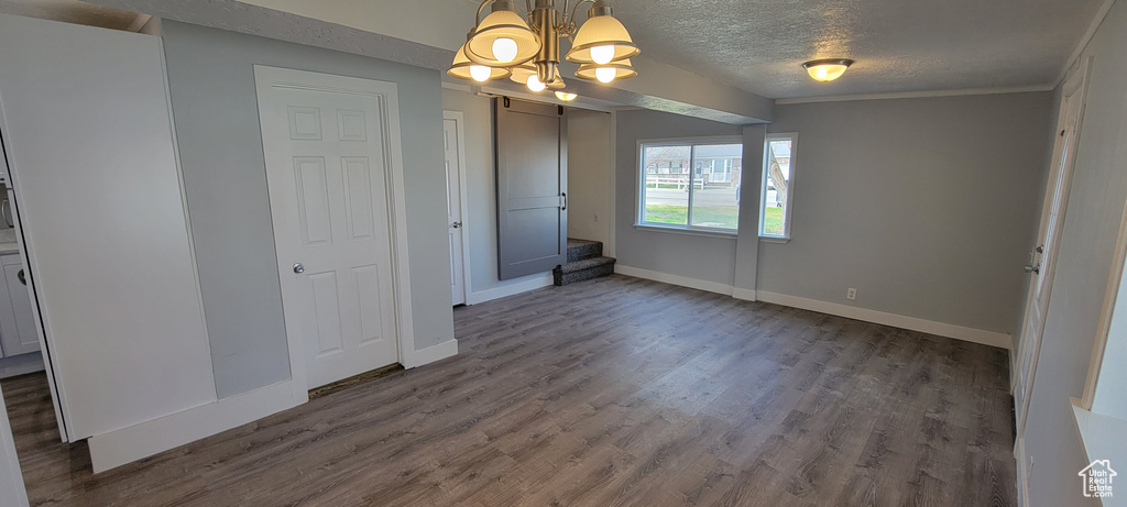 Unfurnished dining area featuring a chandelier, dark wood-style floors, a textured ceiling, baseboards, and stairway