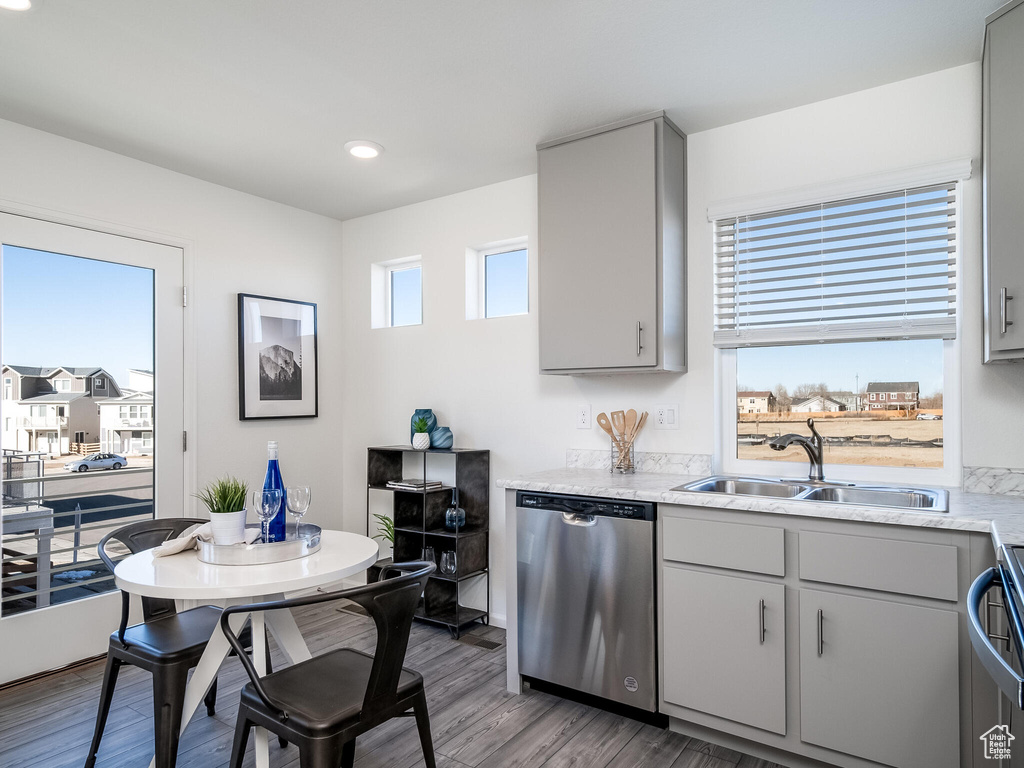 Kitchen with dishwasher, light countertops, wood finished floors, gray cabinetry, and recessed lighting
