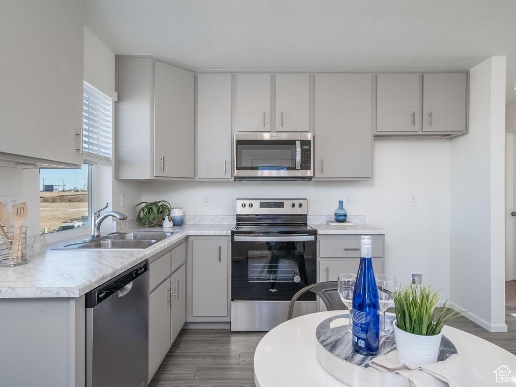 Kitchen with stainless steel appliances, light countertops, gray cabinets, and wood finished floors