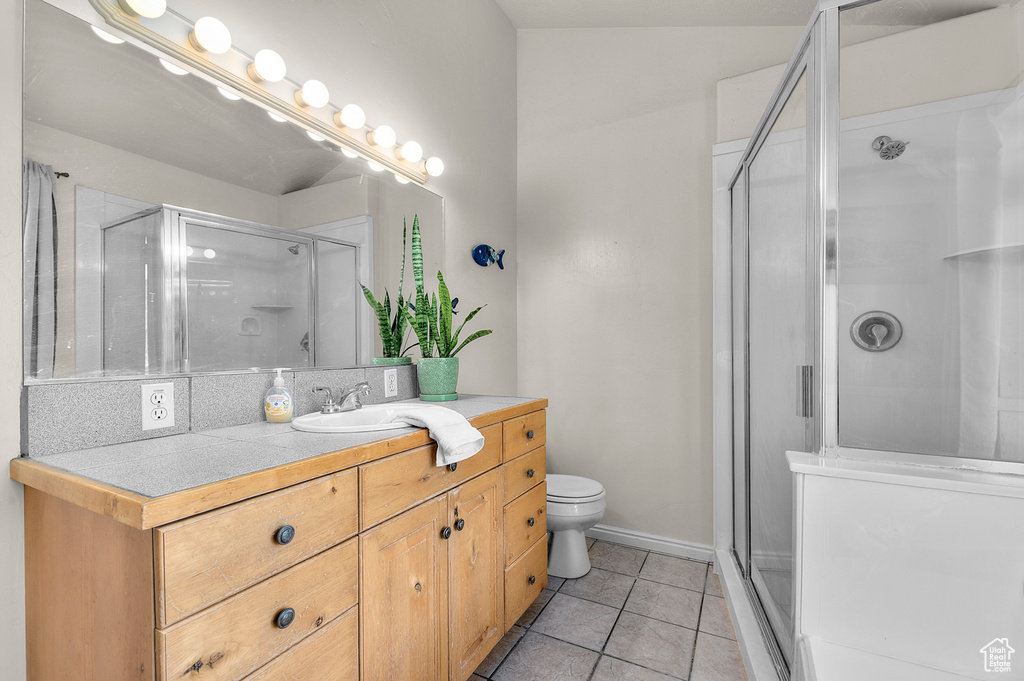 Full bathroom featuring toilet, vanity, tile patterned floors, and a stall shower